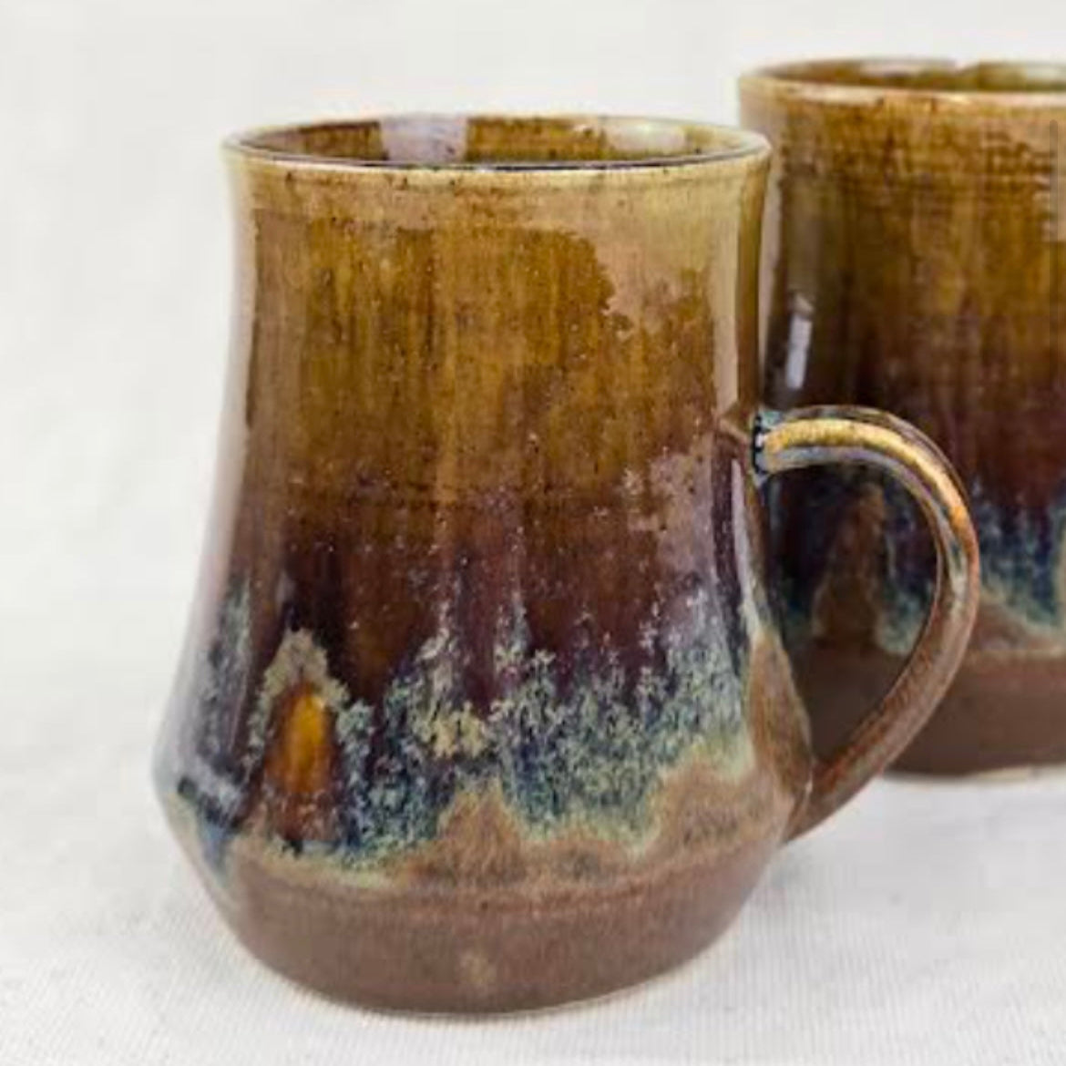 Two brown ceramic mugs with a textured finish on a white background