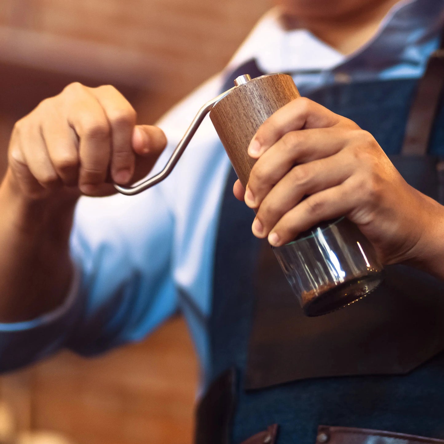 close up of a Barista grinding coffee with a manual coffee grinder