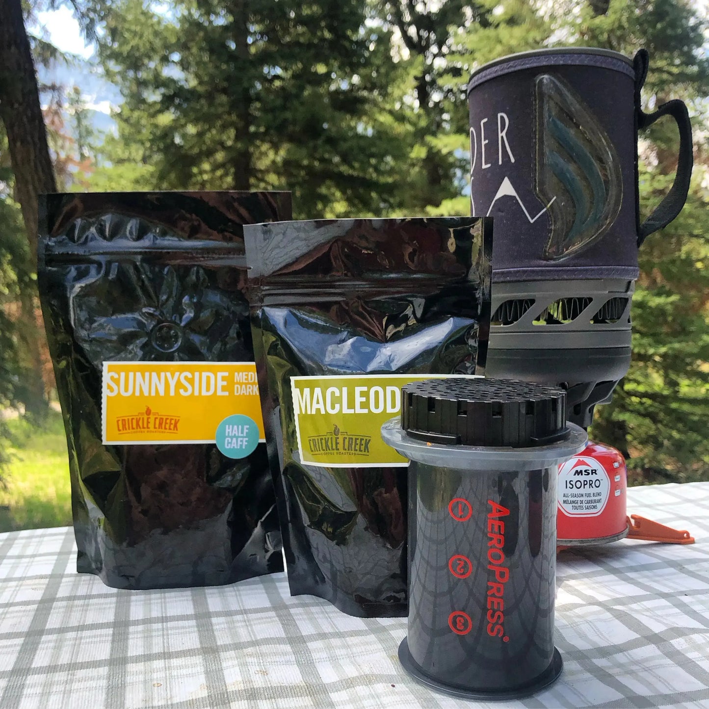 Photo con Crickle. Creek coffee bags on a picnic table with aeropress