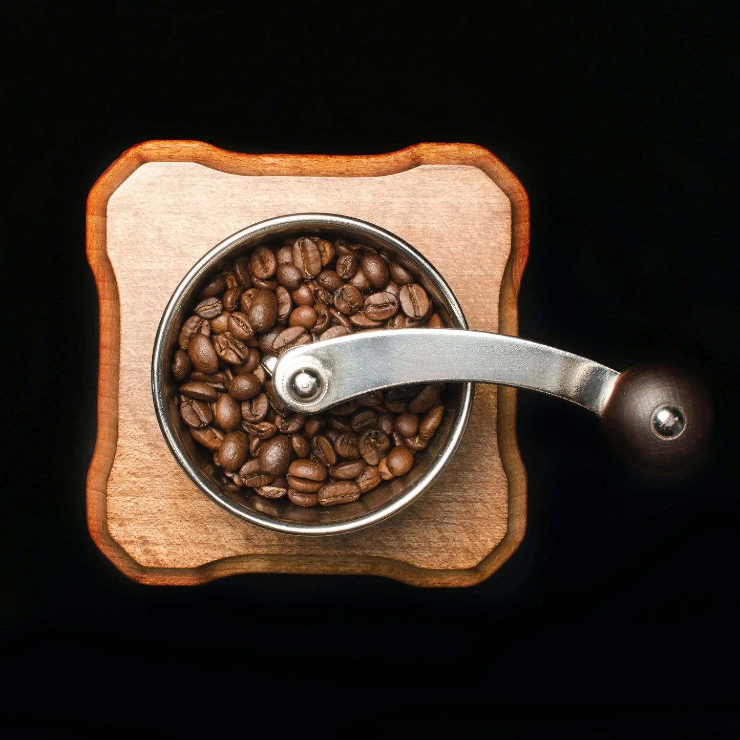 Flat lay out of manual coffee grinder with roasted coffee beans