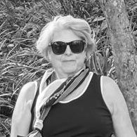 Person wearing sunglasses and a black tank top in a natural setting