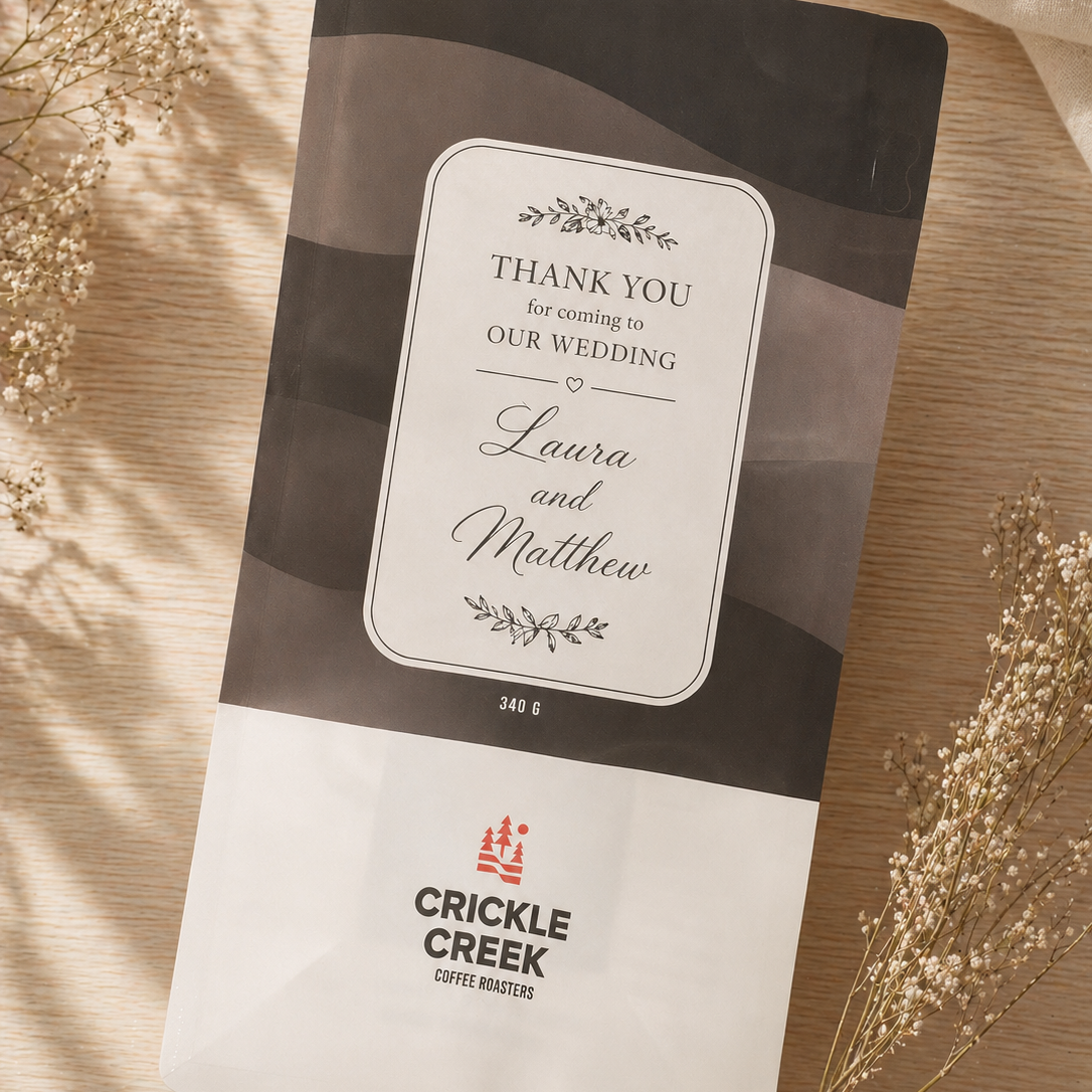 Crickle Creek coffee package with a wedding thank you message on a wooden surface with dried flowers.