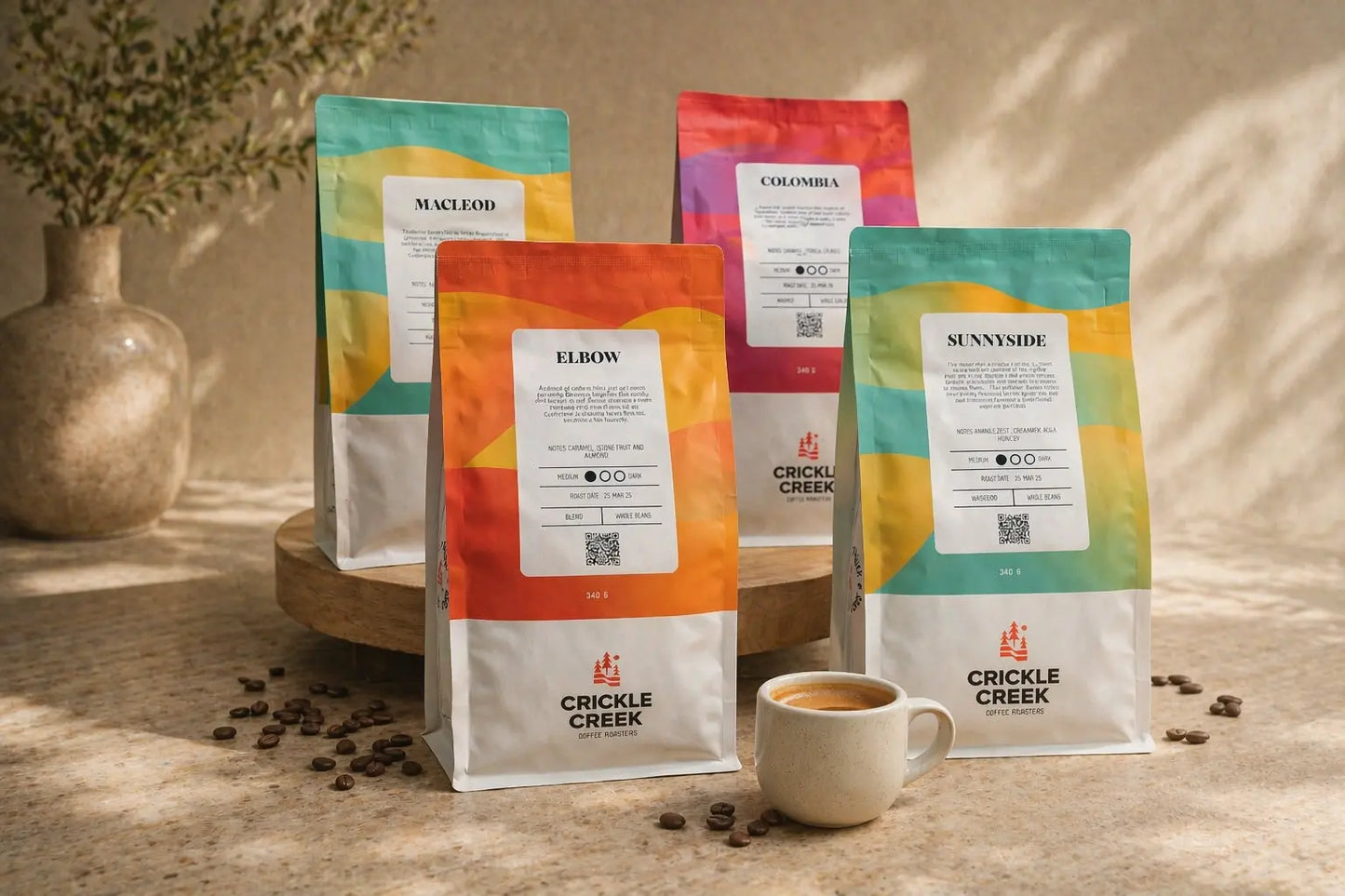 Crickle Creek coffee bags with colorful designs on a wooden surface with coffee beans. Bundle for espresso with colombia coffee