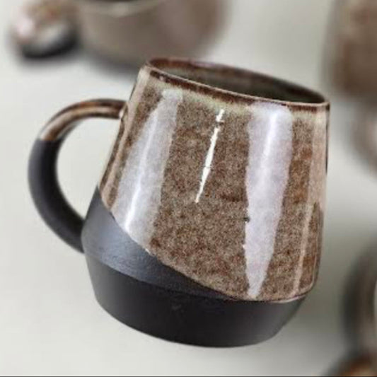 Set of ceramic mugs with brown and black glaze on a light background