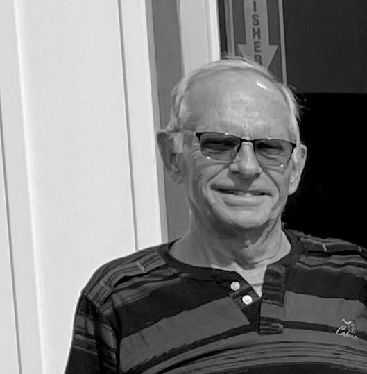 Black and white photo of a man wearing glasses and a striped shirt.