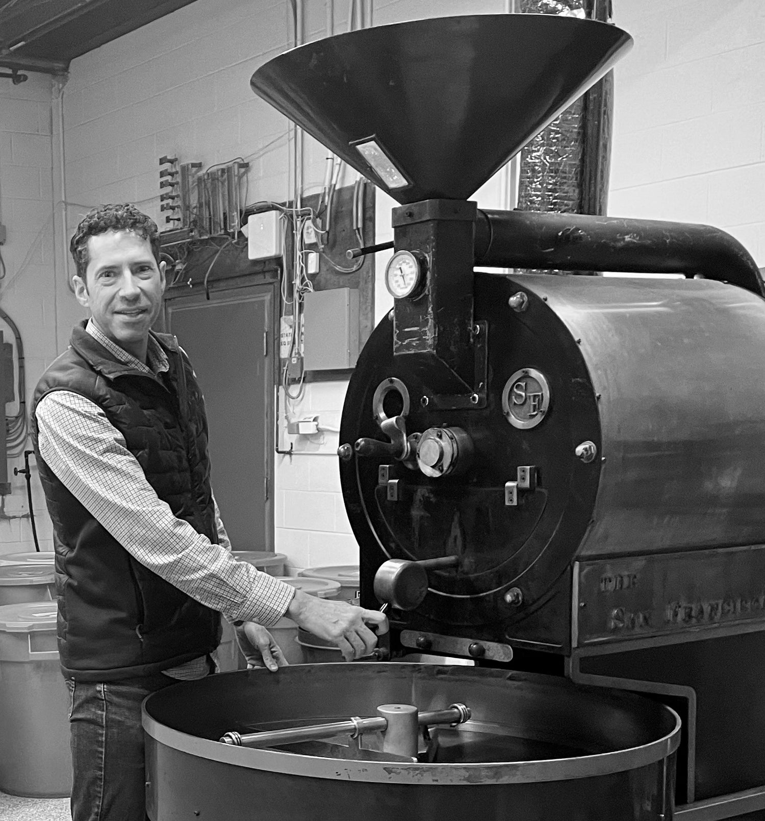 Man operating a coffee roasting machine in a workshop setting