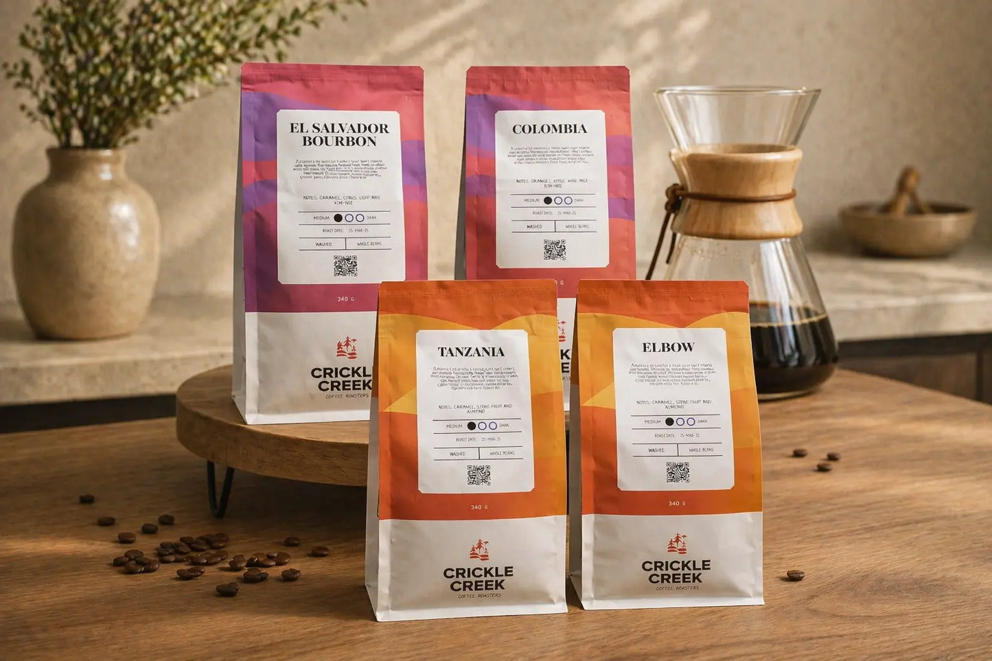 Crickle Creek coffee bags on a wooden table with specialty coffee beans and a Chemex coffee maker. Coffee selected for pour overs