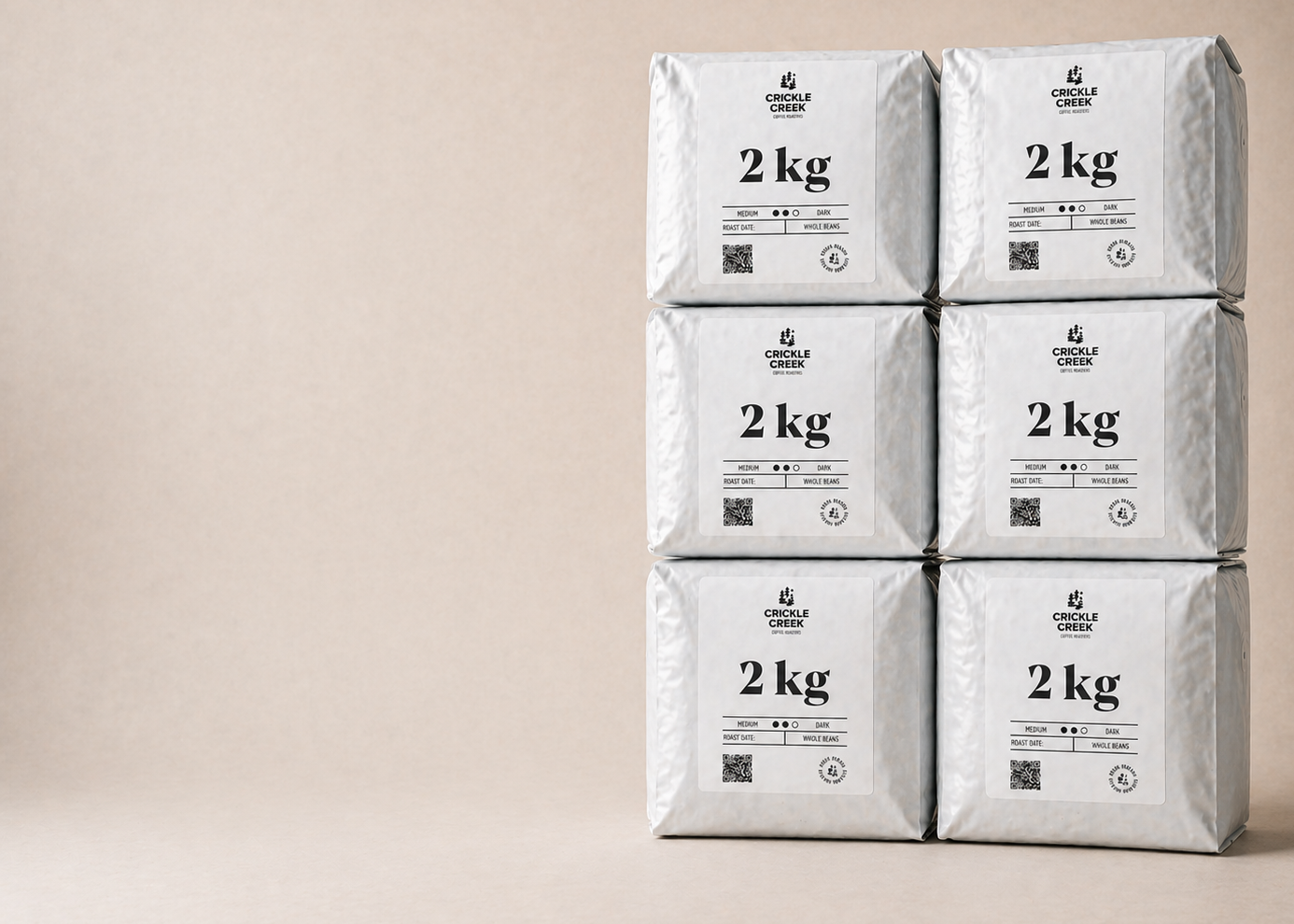 Six 2kg bags of specialty coffee beans freshly roasted stacked on a beige background